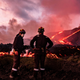 Members of a military emergency unit stand as lava flows from a volcano reaching the sea on the Canary island of La Palma, Spain.